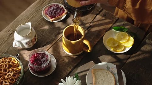 Person Pours Tea on Rustic Wooden Table