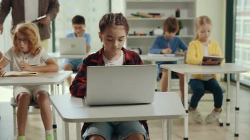 Schulmädchen lernt mit Laptop und sitzt während des Informatikunterrichts im Klassenzimmer