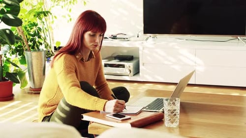 Woman in yellow sweater works at home
