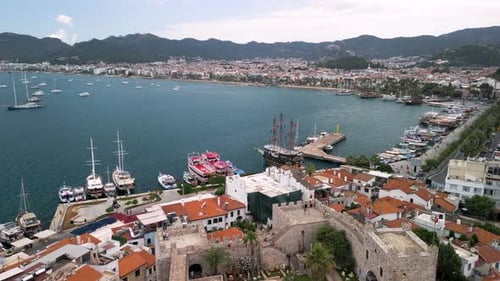 Aerial view of boats and harbor city along coast with mountains, Turkey.
