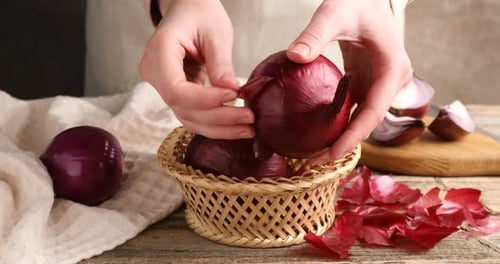 Hands Peeling Shiny Red Onion at Wooden Table