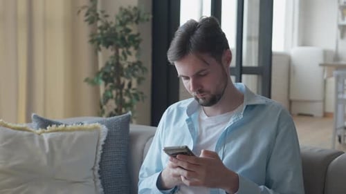 Young Man Using Mobile Phone in Living Room