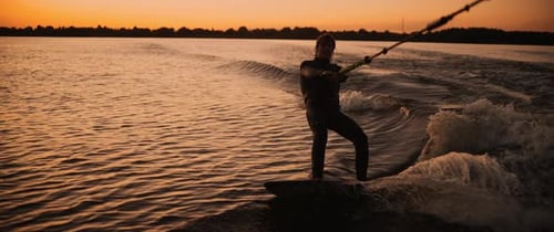 Man wakeboarding on a lake during sunset