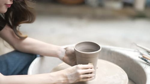 Young women is making earthenware at workshop.