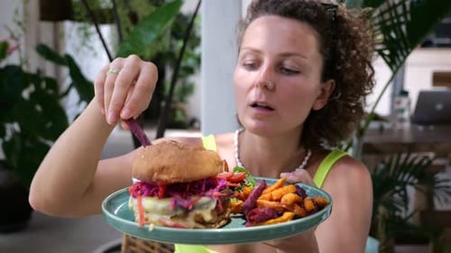 Woman Eats Potatoes and Enjoys the Food Fried French Potatoes Beets and a Juicy Burger on a Plate