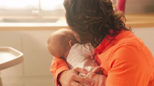 Man Holding Infant in Wheelchair in Kitchen