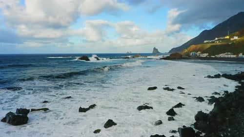 Rocky beach on Tenerife north aerial flight over blue ocean water volcanic wild shore. Black frozen