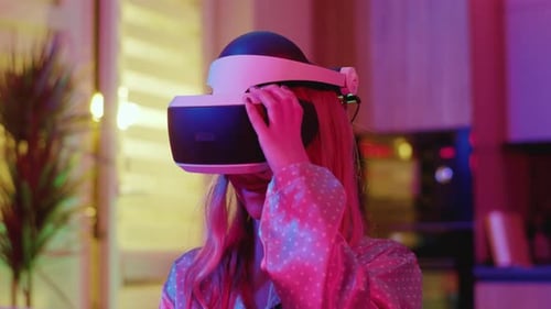 Woman Taking Off VR Headset in Neon Lit Room