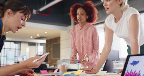 Collaborating on project, diverse women discussing ideas in modern office workspace