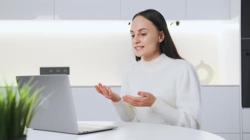 Young Woman Talking on Laptop in White Kitchen