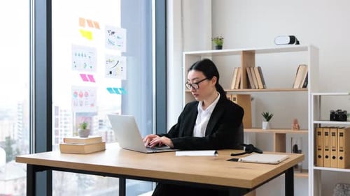 Professional Asian Businesswoman Working on Laptop in Modern Office