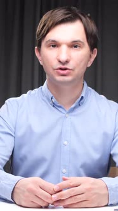 Vertical Video Office Worker Talking and Gesturing at Desk with Folders and Laptop