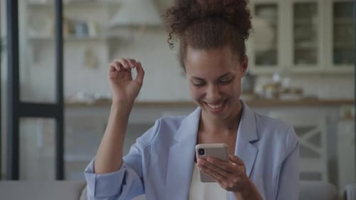 Excited Woman Checks Smartphone in Bright Home