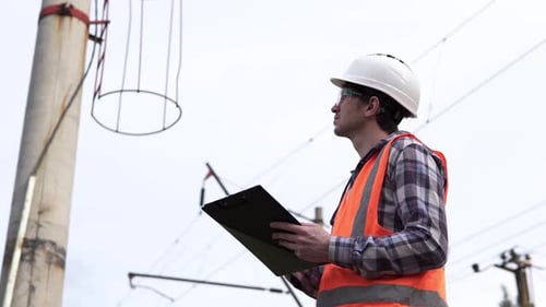 The power engineer inspects the high-voltage power line and records the data.