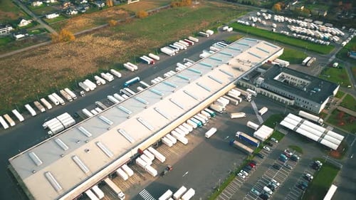 Busy Logistics Hub with Trucks at Large Modern Distribution Warehouse