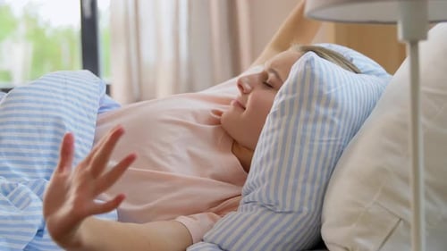Woman Stretching and Yawning in Bed in Bedroom