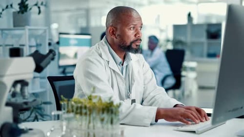 Scientist Typing on Computer at a Desk in Lab