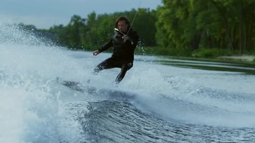 Man wakeboarding behind a motorboat on a river enjoying an extreme summer adventure