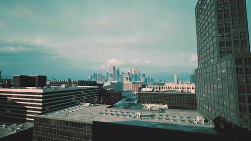 Escena de techo industrial que muestra las rejillas de ventilación y el contorno lejano de la ciudad al anochecer