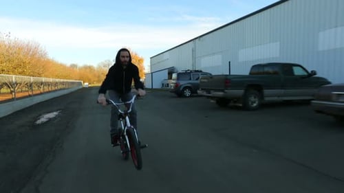 Urban biker performs extreme freestyle tricks on bicycle in dark warehouse