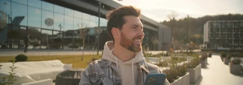 Smiling Man with Phone Outside Urban Building