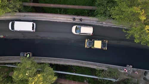 Luftaufnahme des Baus einer neuen Straße, als Asphaltpflaster, Walzen, Maschinen und Arbeiter kommen