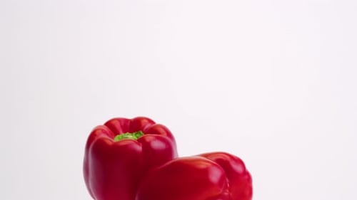 Red Bell Peppers Falling on White Background