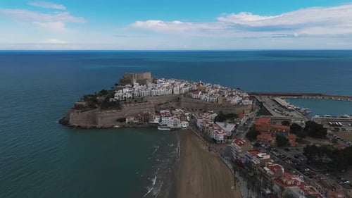 Evening aerial of castle in golden light and crashing waves