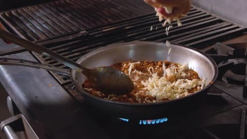 Hand pouring shredded cheese into pan with salsa. Salsa sprinkled with cheese in slow motion. Shredd