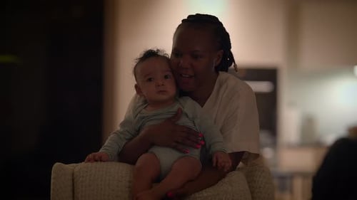 Loving Mother Cradles Baby in Armchair