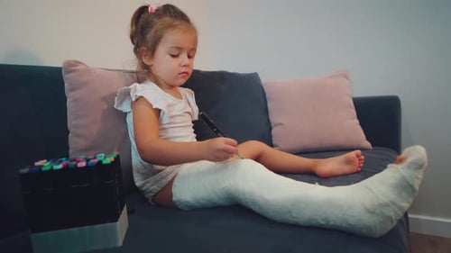 Girl Draws on Her Leg Cast on Couch
