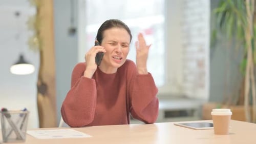 Woman Talking on Smartphone at Desk Indoors