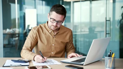 Busy financier or accountant making financial calculations using typing on a laptop computer, taking