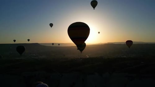 Hot Air Balloons Flying at Sunrise over Landscape