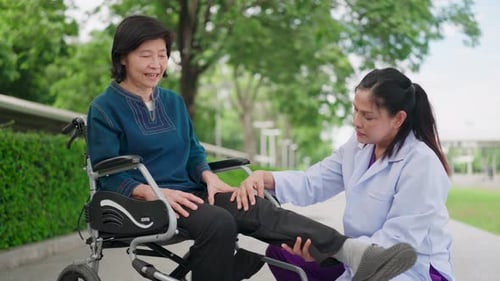 Caregiver Assists Senior Woman with Leg Exercise Outdoors