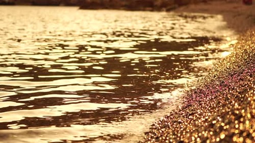 Abstrakter Meeres-Sommer-Sonnenuntergang Natur-Hintergrund Kleine Wellen auf goldener Wasseroberfläche in Bewegung