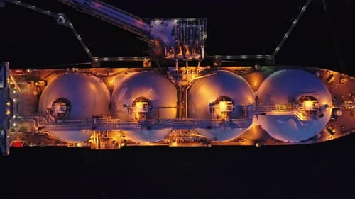 Aerial of Liquified Natural Gas LNG Carrier Moored to a Small Gas Terminal at Night Fuel Crisis