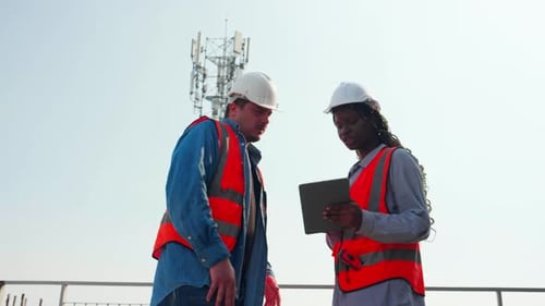 Team young engineer walking inspection construction site and talking while looking laptop.
