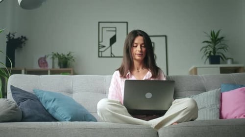Woman Using Laptop Sitting Cross-Legged on Sofa