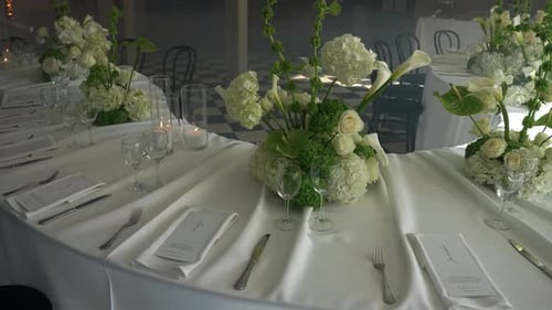 Elegant wedding table setup with lush white floral centerpieces, fine glassware, and formal place