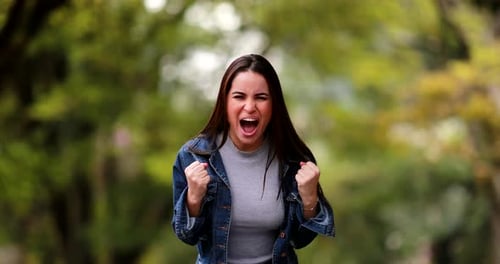Excited Woman Celebrates in Park Wearing Denim Jacket