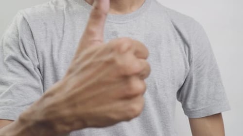 Hand Gives Thumbs Up in Front of Shirt