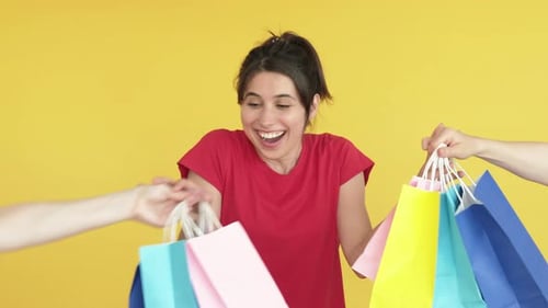 Excited Woman Receives Shopping Bags on Yellow Background