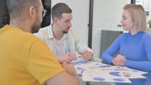 Team Discussing Charts at Workplace Meeting