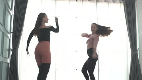 Friends practice ballet dance at studio.