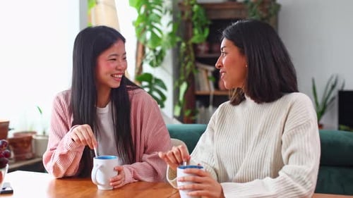 Two Young Women Chatting Over Coffee at Home