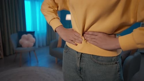 Woman Massaging Abdomen Experiencing Pain Indoors