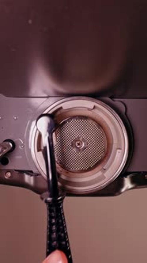 Vertical video. Slow Motion Bottom View Of Espresso Machine Group Head Being Cleaned With Brush
