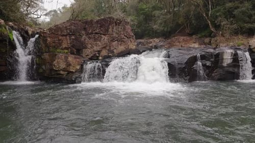 Beautiful waterfalls in the nature, surrounded by stones, drone flight over the water surface, river