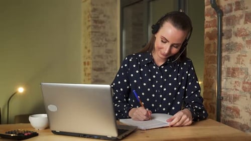 Young Adult Female Writing in Notebook at Desk
